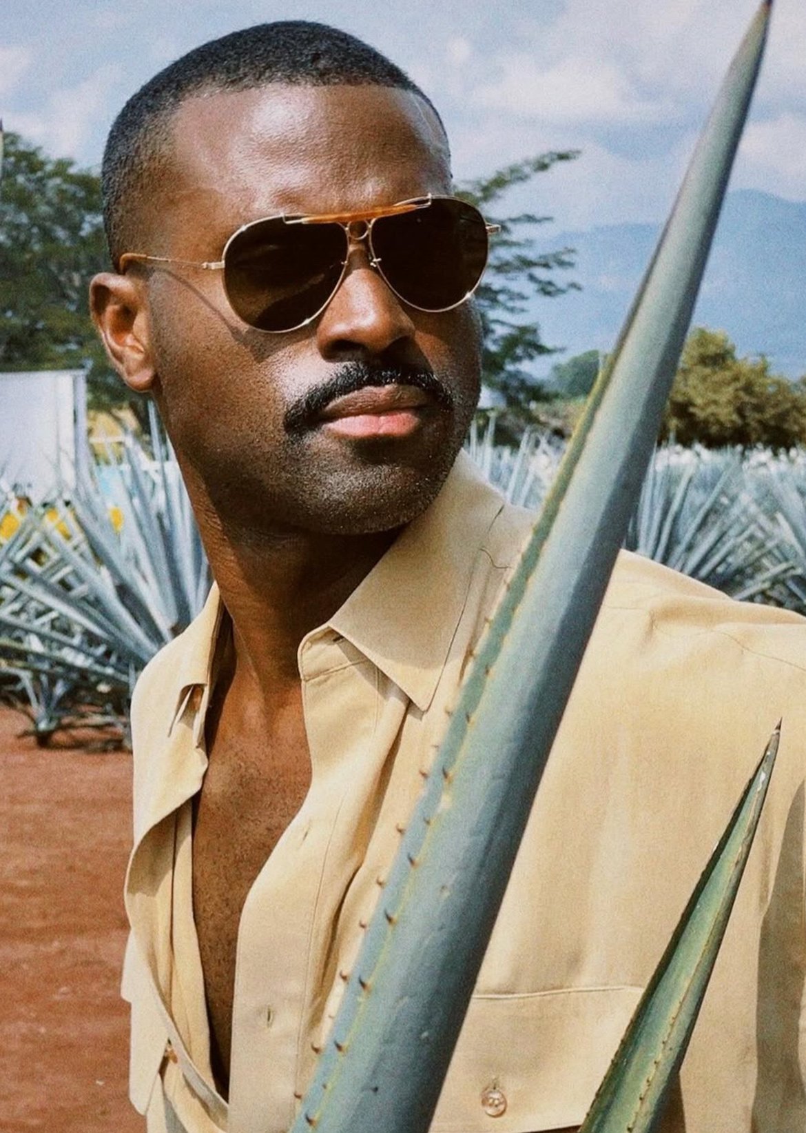 black man wearing gray sunglasses looking up into a blue sky