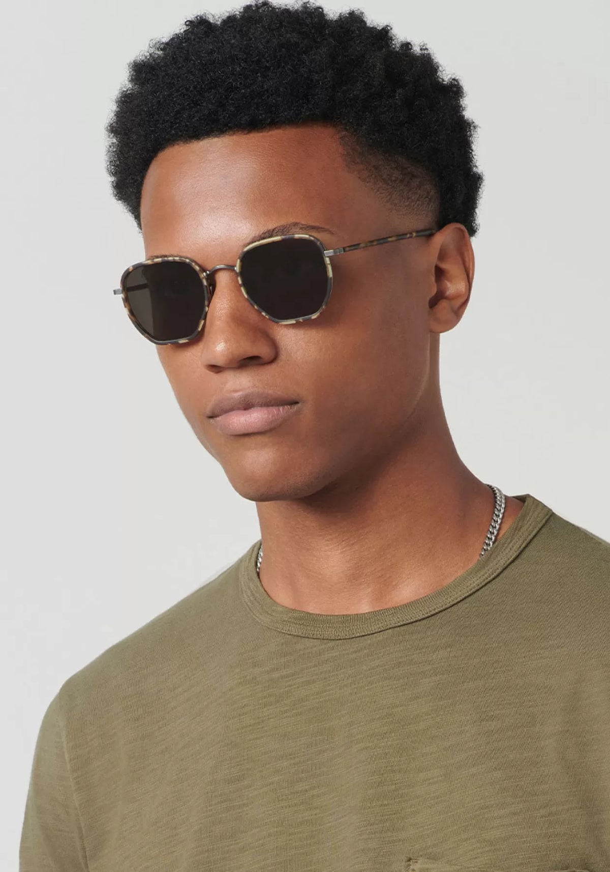 black man wearing gray sunglasses looking up into a blue sky