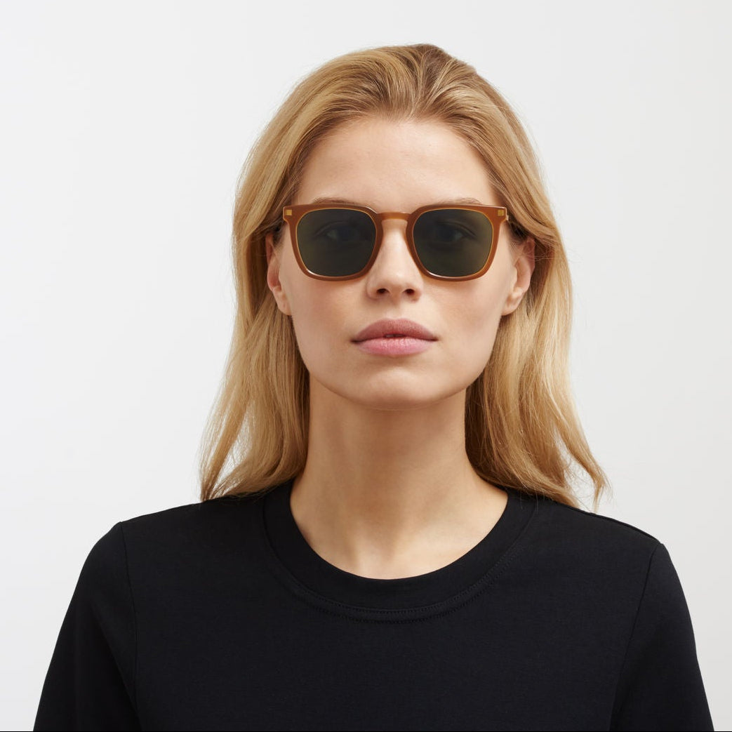 Woman wearing sunglasses and a black top on a white background